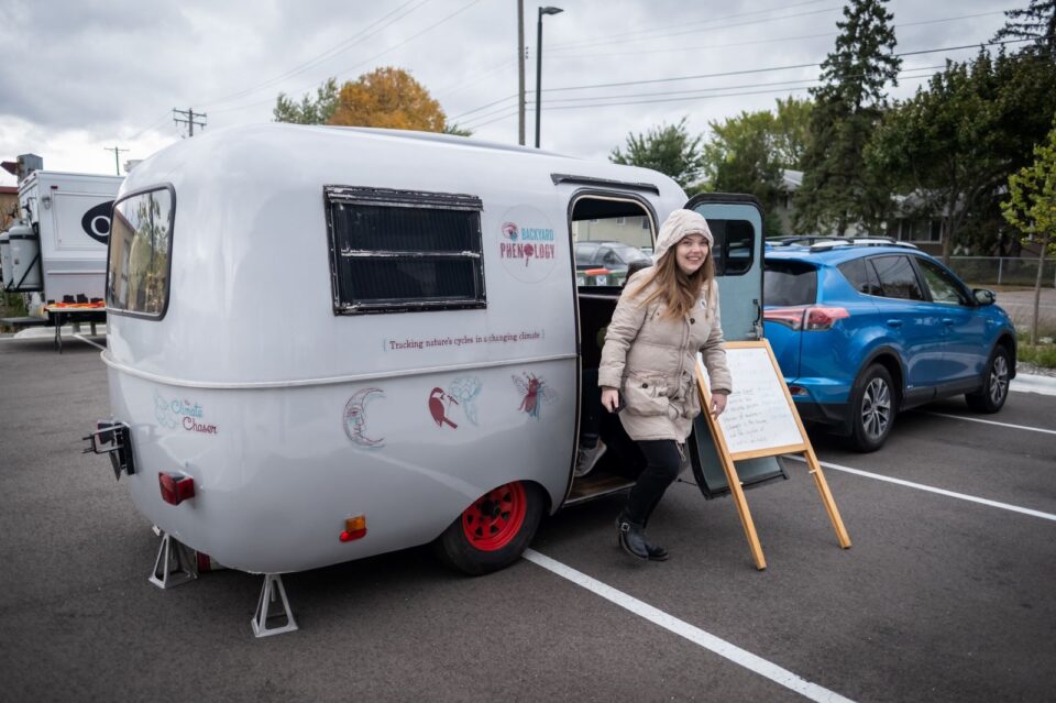 A person steps out of a small, camper trailer with 